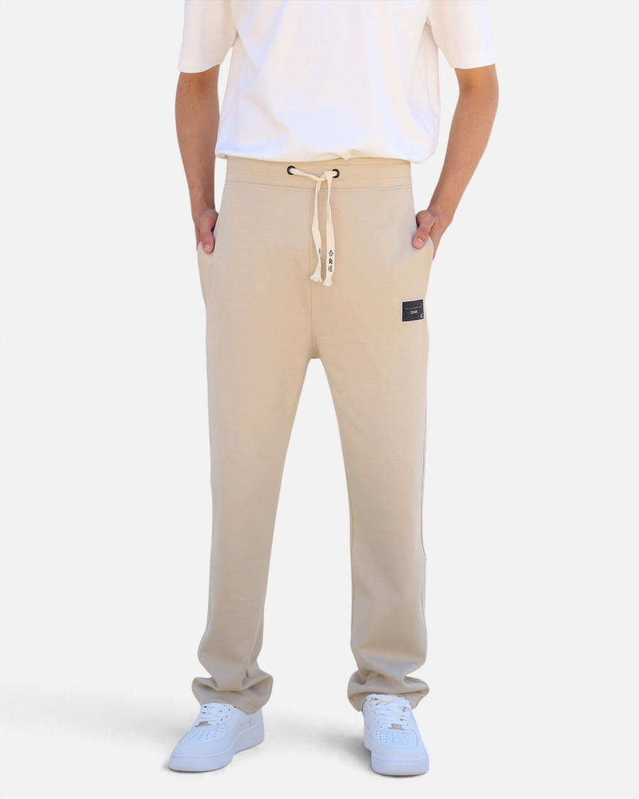 RUVR beige heavyweight fleece sweatpants with Japanese-script drawstring, side pockets, and woven label patch.