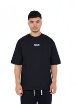 Model wearing a black RUVR oversized heavyweight cotton t-shirt with a centered white wordmark logo on the chest.