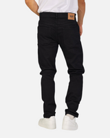 Back view of a man wearing RUVR black heavyweight cotton twill straight-fit jeans with a tan leather brand patch.