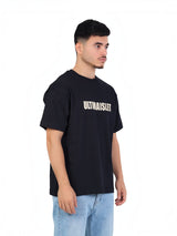 RUVR Bloc Tee in black heavyweight cotton with bold block-letter chest graphic, worn by a man in a side profile view.