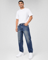 RUVR Ease relaxed fit blue denim jeans on a male model wearing a white t-shirt and white sneakers