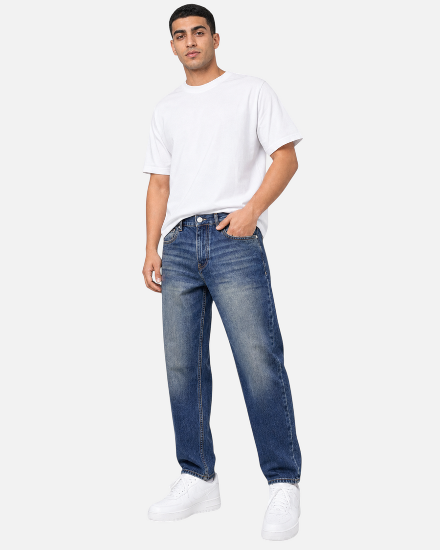 RUVR Ease relaxed fit denim jeans in blue with a tapered leg, worn by a man with a white t-shirt and sneakers.