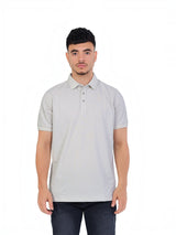 A model wearing a light grey RUVR Essential Polo shirt in cotton piqué with a tonal embossed chest emblem.