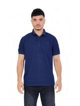 A model wearing a navy blue RUVR Essential Polo shirt in cotton piqué with a tonal embossed chest emblem.