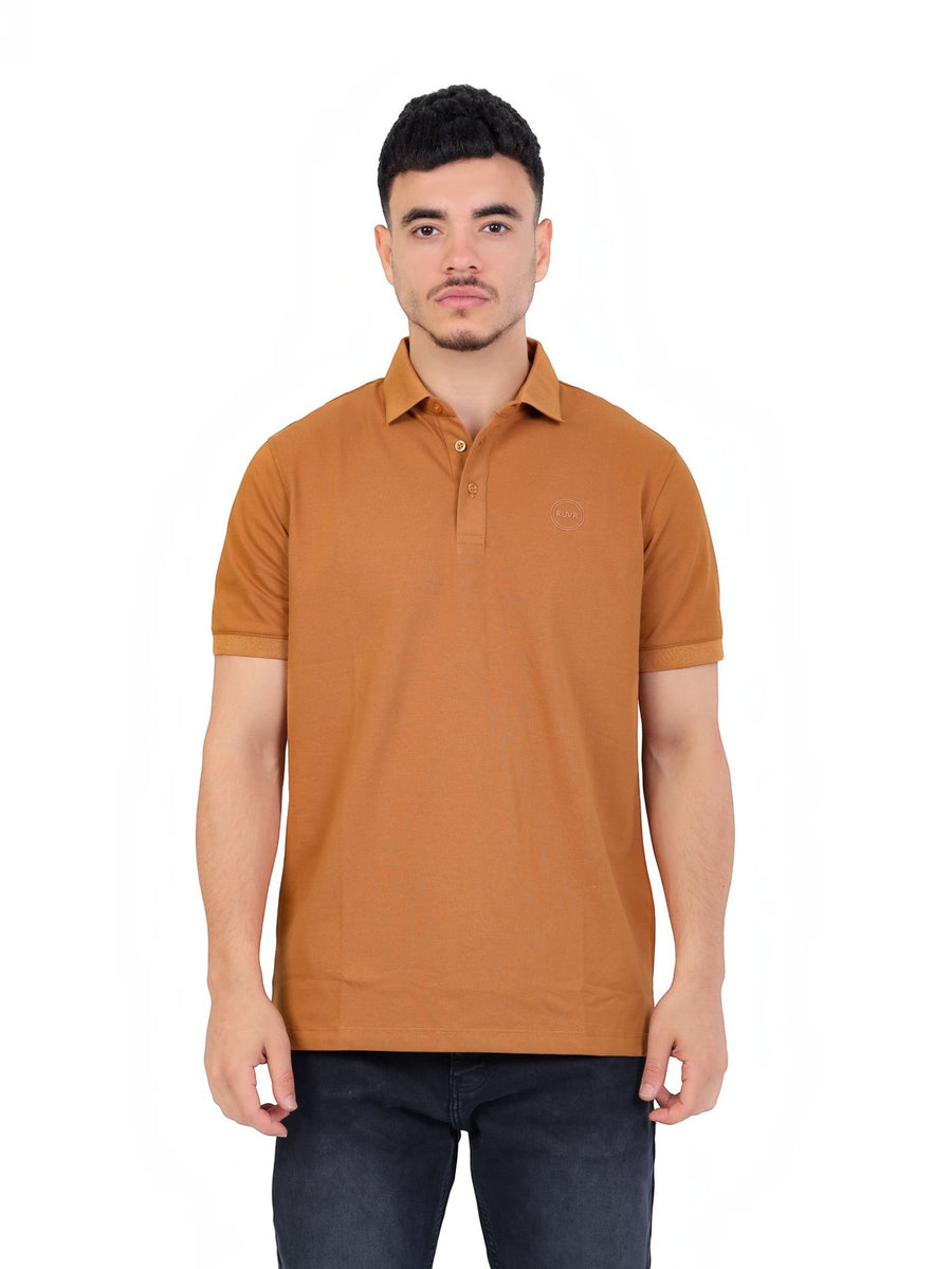 A man wearing a RUVR Essential Polo in tan cotton piqué with a tonal embossed emblem, classic collar, and ribbed cuffs.