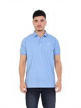 A model wearing a light blue RUVR Essential Polo shirt in cotton piqué with a tonal embossed emblem and ribbed cuffs.